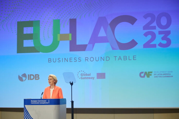 Ursula von der Leyen hablando en la 3.ª cumbre UE-CELAC 2023 en Bruselas, con el logo EU-LAC 2023 proyectado detrás, sobre la iniciativa Global Gateway y la cooperación birregional UE-América Latina.
